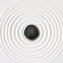 Galet noir sur cercle en sable blanc épuré illustrant le minimalisme appliqué aux soins naturels certifiés COSMOS NATURAL ou ORGANIC – KALYAË ORIGIN