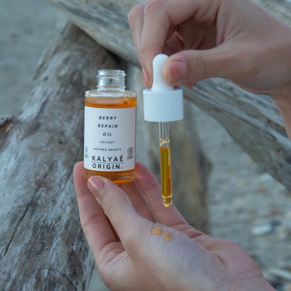 Berry Repair Oil huile régénérante visage certifiée COSMOS ORGANIC 30 ml présentée en mise en situation en extérieur sur fond de bois naturel – KALYAË ORIGIN
