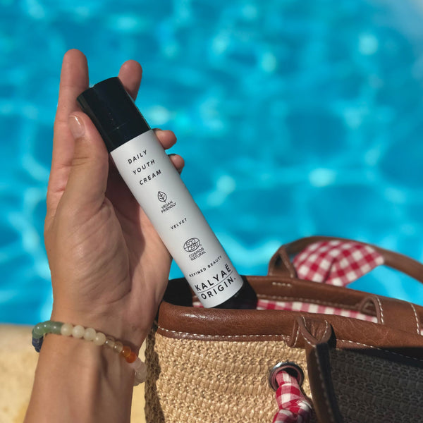 Daily Youth Cream crème anti-âge hydratante certifiée COSMOS NATURAL 50 ml présentée en application en extérieur près d’une piscine – KALYAË ORIGIN
