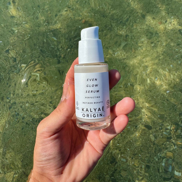 Even Glow Serum unifiant éclat certifié COSMOS NATURAL 30 ml présenté en application en extérieur à la mer – KALYAË ORIGIN
