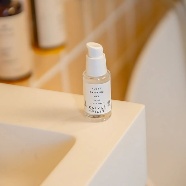 Pulse Caffeine Gel contour des yeux défatigant certifié COSMOS NATURAL 30 ml présenté en application près d’un lavabo – KALYAË ORIGIN
