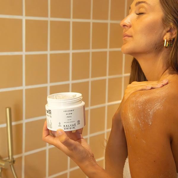 Volcanic Glow Peel gommage purifiant pour le corps certifié COSMOS NATURAL 170 ml présenté en application dans une salle de bain – KALYAË ORIGIN